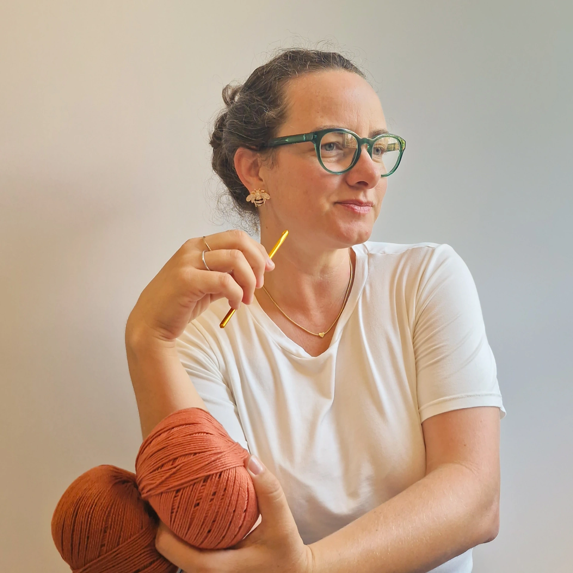 Aline, criadora da MissiCat Crochê, com fio terracota nos braços